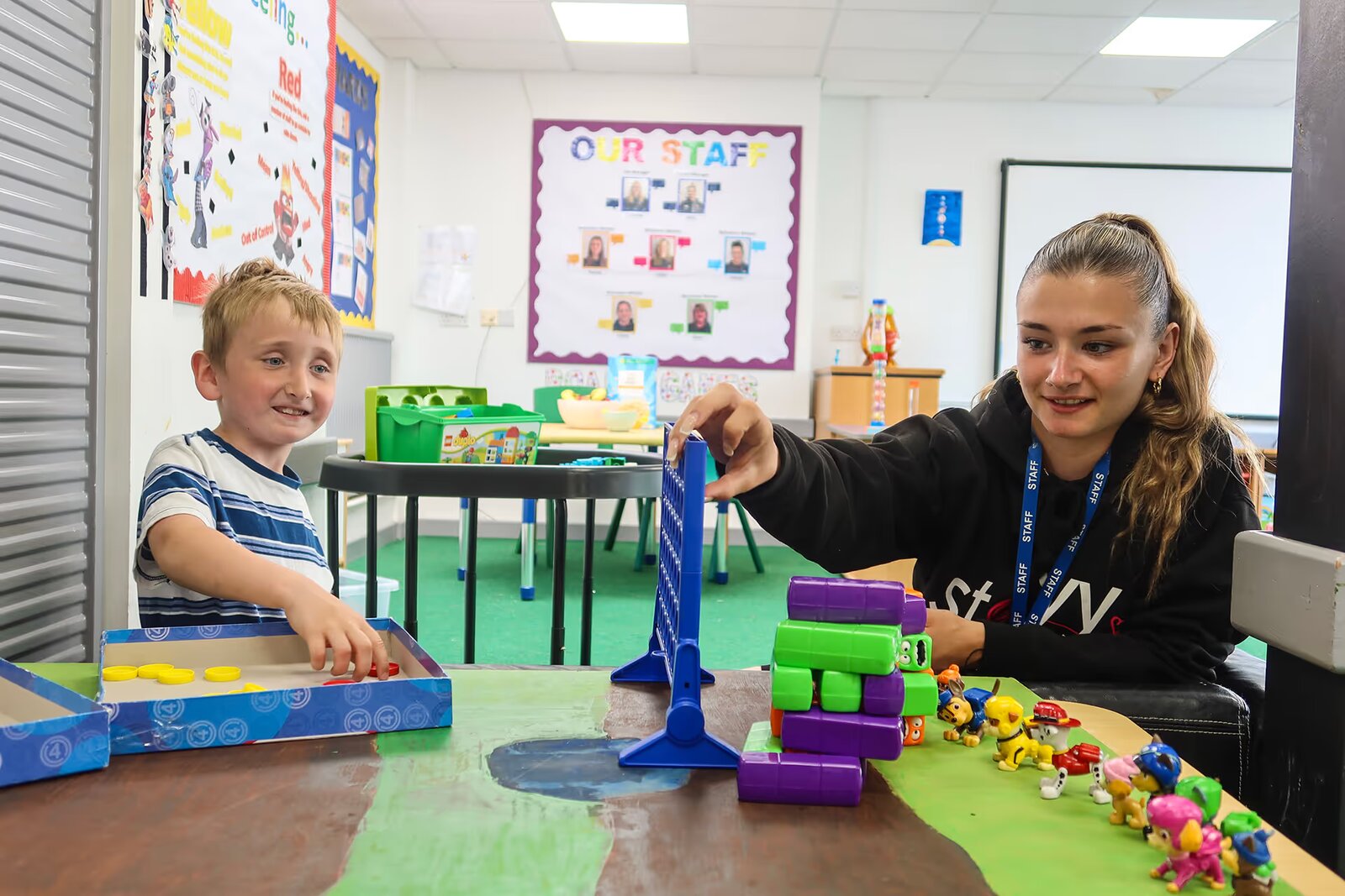 A staff member playing Connect 4 with a young pupil