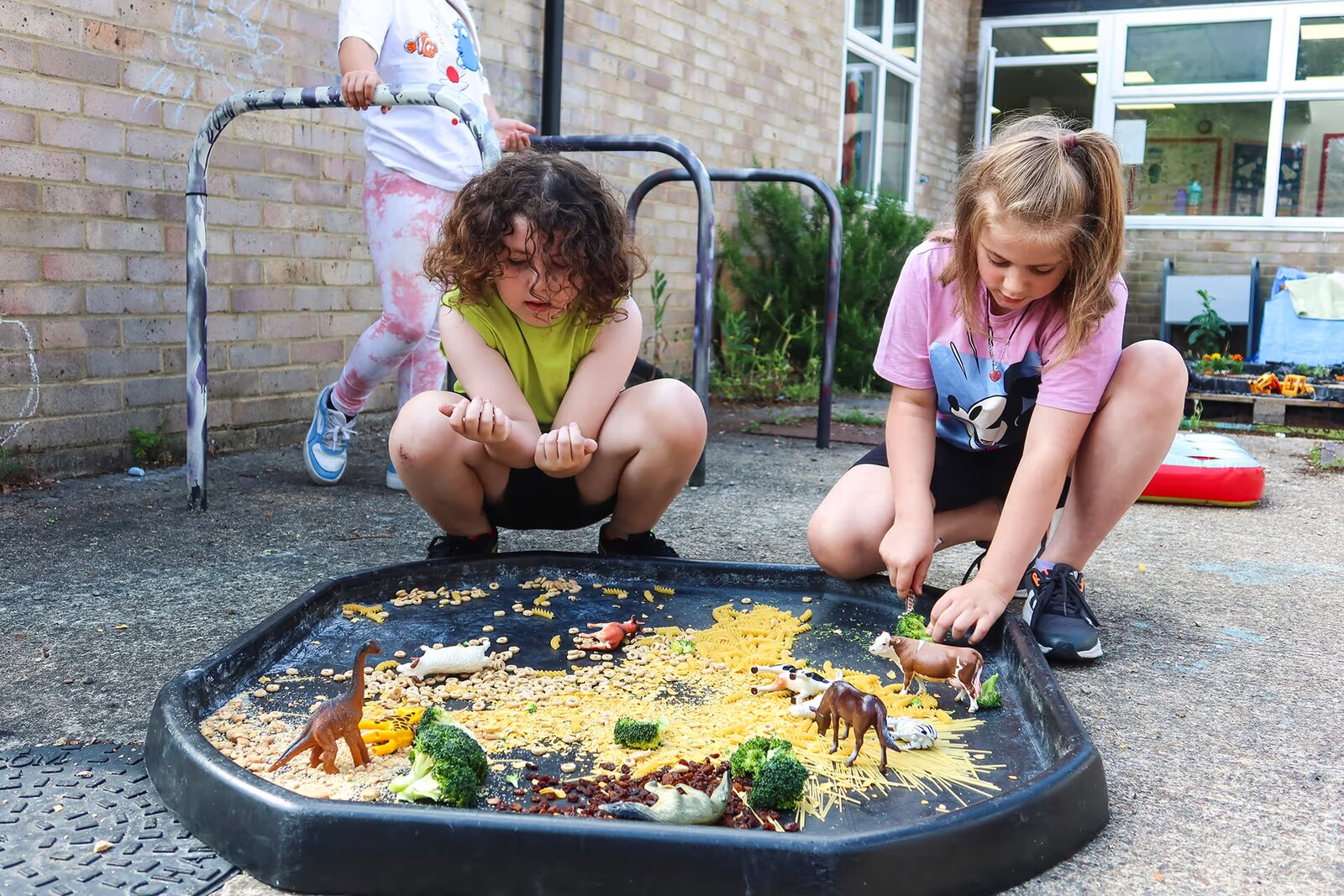 Pupils exploring a sensory tuff tray outdoors